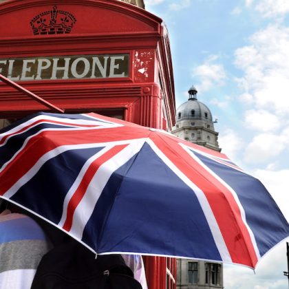 Tourist with British umbrella in telephone box and Big Ben in London